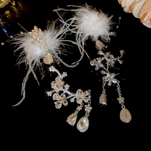 Close-up of silver rhinestone flower earrings with white feathers and teardrop crystal