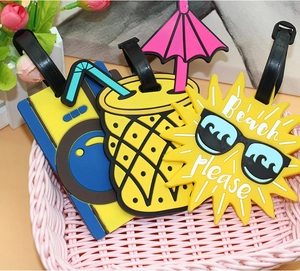 Close-up of cartoon pineapple and sun PVC luggage tags in a small pink basket