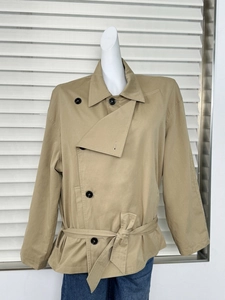 Close-up of khaki short trench coat with double-breasted buttons and waist belt detail