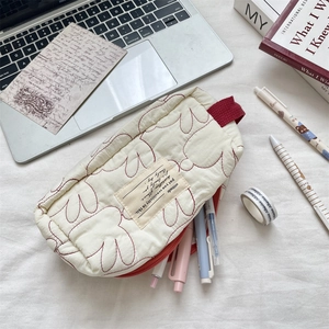 Primer plano de estuche acolchado con cremallera roja y asa sobre un escritorio