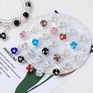 Detailed view of silver DIY jewelry charms with colorful crystals on marble coaster