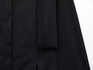 Macro shot of black fabric texture with subtle sheen and side slit detail on trousers