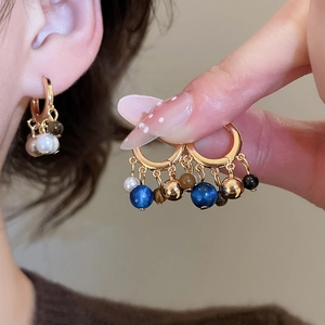 Detail of 18k gold plated hoop earrings with tiger eye and pearl bead tassel pendants