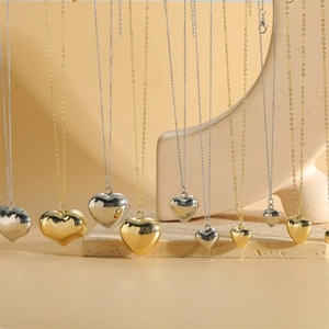 Minimalist gold and silver heart pendant necklaces on an elegant stone display stand