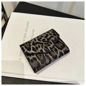 Mini borsa a busta leopardata su sfondo di libri, accessorio moda trendy per donna 2024