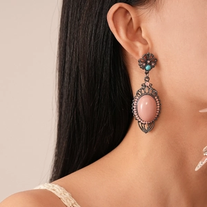 Detail shot of vintage bohemian earrings with pink acrylic stone and carved metal frame