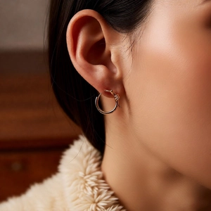 Close-up of 18k gold plated hoop earring with crystal infinity knot detail on model