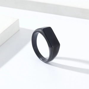 Close-up of a minimalist black square signet ring on a clean white geometric surface