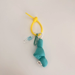 Detail of teal knotted doll keychain with yellow silicone ring and colorful plastic chain