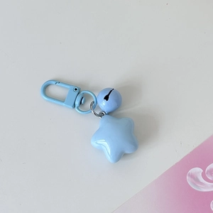 Macro detail of a light blue star-shaped bell keychain with smooth lacquer finish