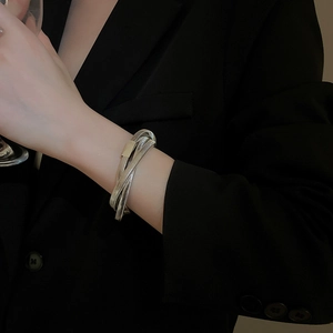 Macro detail of silver layered spiral metal bracelet on black blazer sleeve
