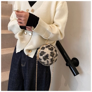 Close-up of leopard print ball bag featuring gold metal ring handle and chain strap