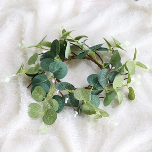 Close-up of faux eucalyptus wreath with white berries on soft white fabric background