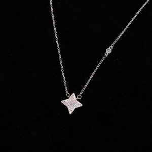 Close-up of silver four-pointed star pendant necklace with crystal zircons on black background