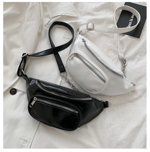 Detail view of black and white PU leather waist bags with silver chain and dual zippers