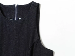Detailed close-up of dark blue denim dress zipper neckline and size S garment tag
