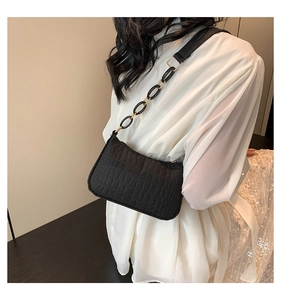 Detail of a chic black embossed underarm bag with gold and black chain strap on shoulder