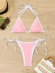 Close-up of pink textured bikini with white piping on a summer wooden background