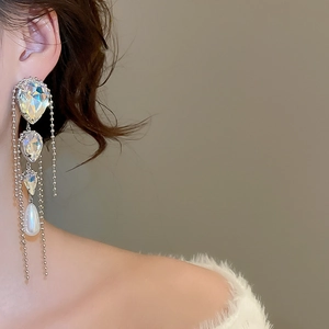 Long silver tassel earrings with crystal drops and a white pearl on a model