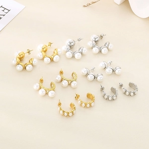 Detailed view of assorted C-shaped stainless steel earrings with pearl accents in gold and silver