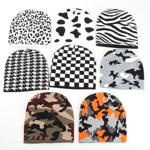 Flat lay of knit beanies in camo, leopard, and houndstooth patterns for winter warmth