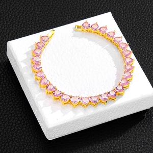 Close-up of gold tennis chain necklace with pink heart-shaped stones on jewelry box