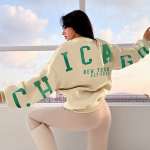 Détail de l'imprimé Chicago vert sur un sweat-shirt en coton beige de coupe ample