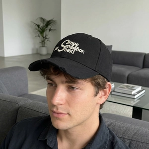 Distressed black vintage baseball cap with white letter embroidery shown on a male model