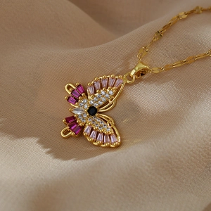 Macro view of butterfly pendant with pink stones and micro-set diamonds on gold chain
