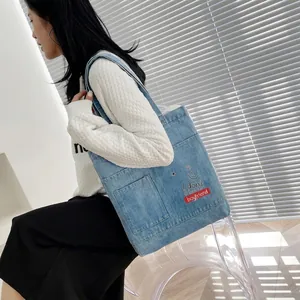 Detail of light blue denim tote bag with I don't have a boyfriend embroidery