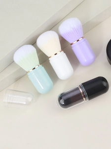 Detail of four colorful capsule-shaped portable makeup brushes with soft synthetic bristles