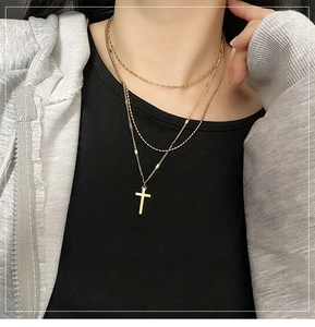 Close-up of a layered gold titanium steel triple chain necklace with a cross pendant