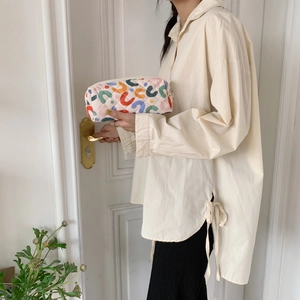 Borsa da trucco trapuntata con motivi floreali tenuta da una donna in un ambiente luminoso