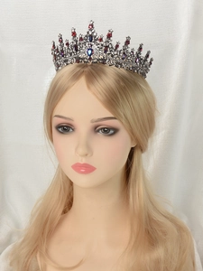 Detailed view of vintage black gold crown with red and blue gems on a mannequin head
