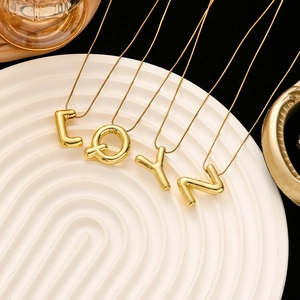 Detail of high-polished gold initial pendants L Q Y N on delicate snake chains