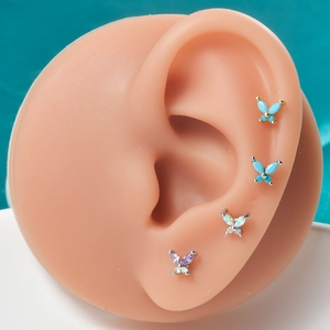 Detailed set of butterfly stud earrings with turquoise and opal stones on model ear