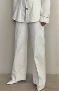 Detailed shot of white wide-leg trousers with button accents and a draped fit