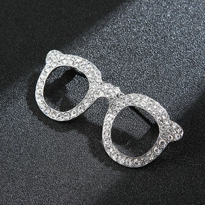 Detail of sparkling rhinestone encrusted cat-ear glasses brooch on textured black background