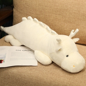 Detail of soft white dragon plush pillow resting on a sofa with cozy home decor