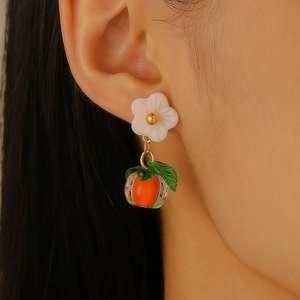 Close-up of sweet persimmon and white flower earrings on model with warm tones