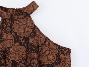 Détail du tissu gaufré floral marron sur une robe à col montant avec des volants
