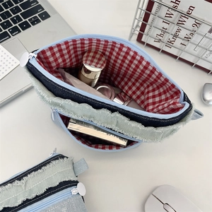 Detail der Jeans-Kosmetiktaschen mit rotem Karo-Innenfutter und Reißverschluss-Design