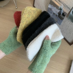 Close-up of knit fingerless gloves in multiple vibrant colors on a wooden table