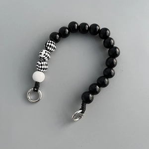 Detail of checkerboard wood beads and black polished beads on a short phone strap