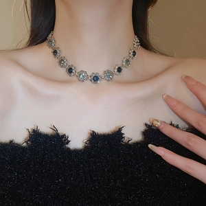 Close-up of vintage flower necklace with blue crystals on gold choker chain for women