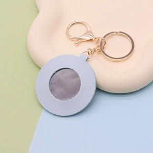Detail of light blue faux leather keychain mirror with gold metal ring and clear reflection