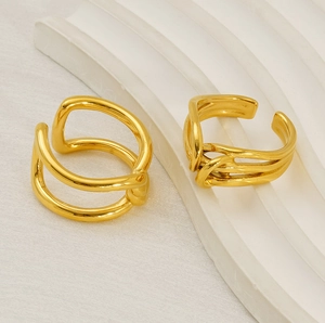 Detail of adjustable golden wave rings on white textured stone with minimalist aesthetic