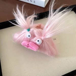 Close-up of a pink plush monster hair claw clip with large eyes and furry braids detail