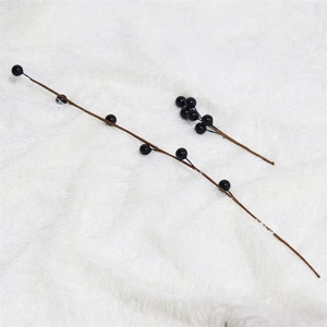 Detail of two artificial black berry branches on a white plush rug for home decoration