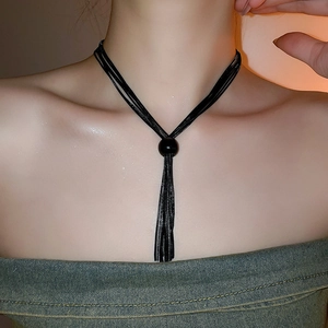 Dettaglio del choker a più strati in corda nera con perla e nappa lunga e fluida